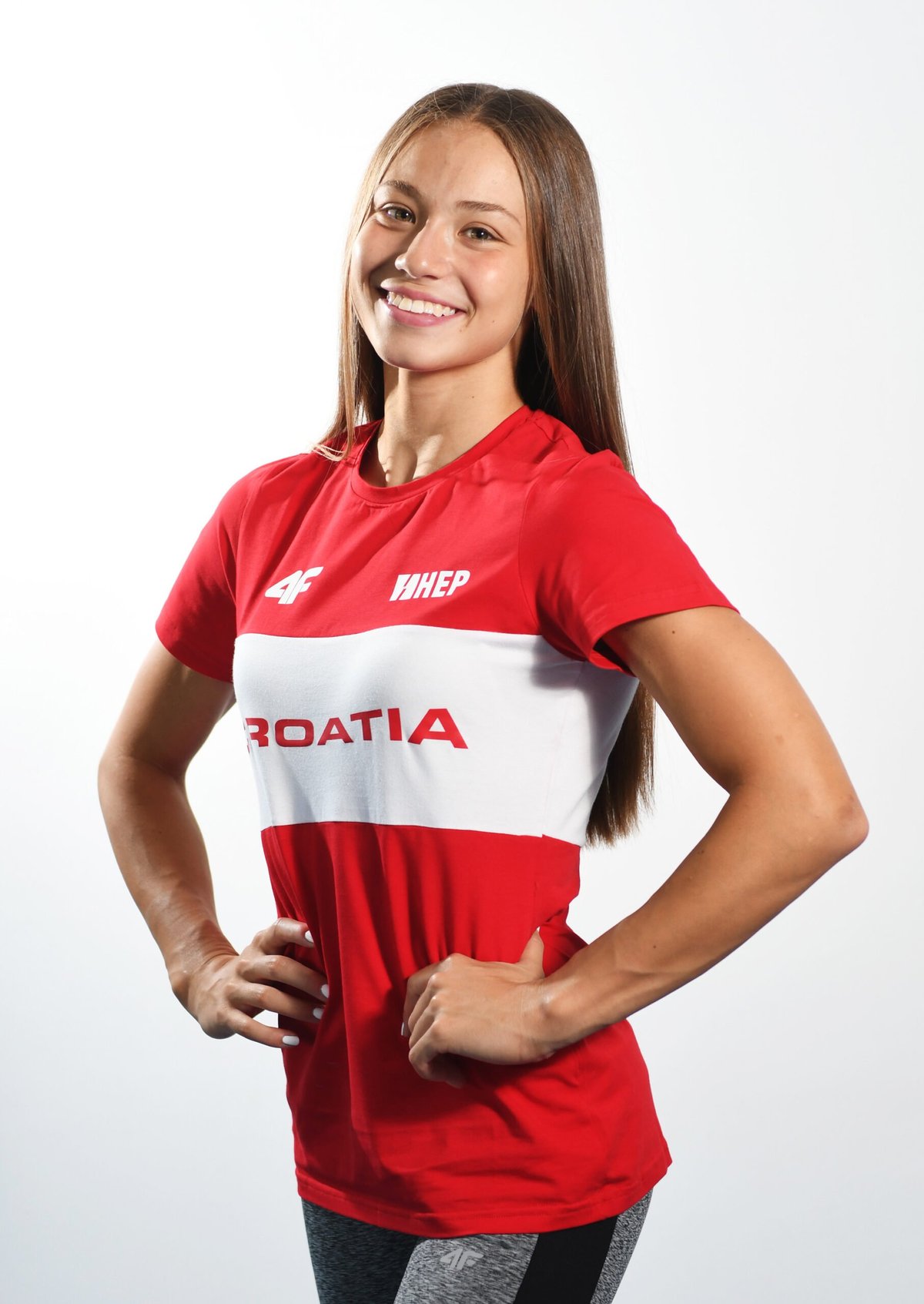Young woman wearing a red and white Croatia sports jersey, smiling at the camera against a white background